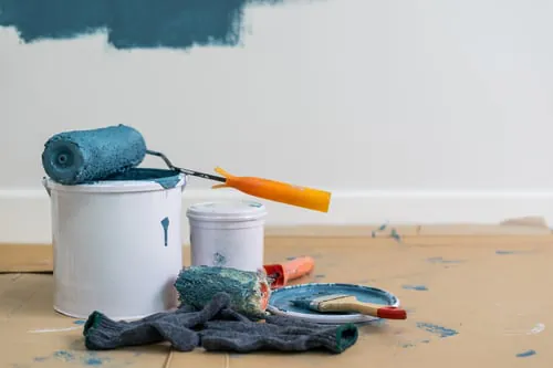 Paint roller resting on a can over a drop cloth during interior prep